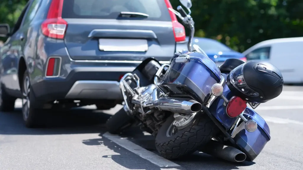 Motorcycle crash on the road with a car parked behind it