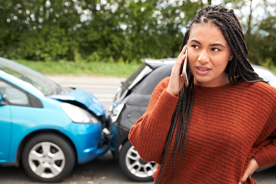Woman calling the insurance company from the side of the road after a car accident