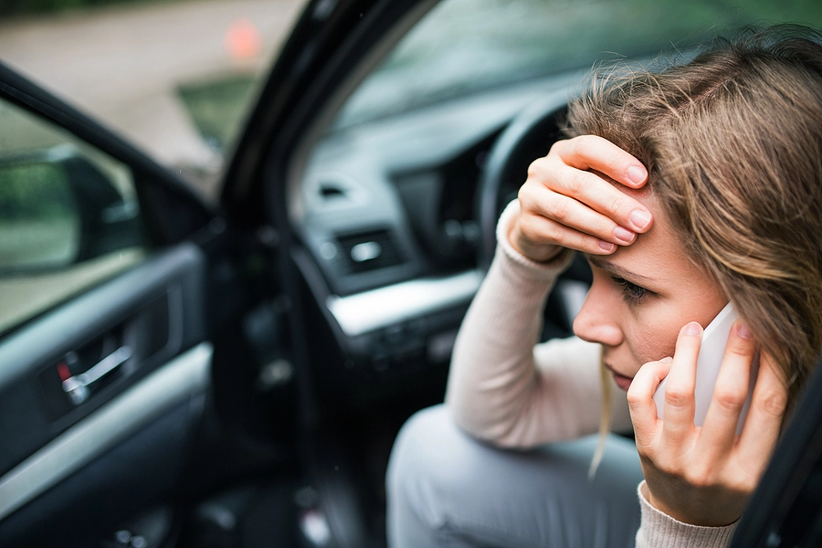 Stressed woman talking on the phone after a car accident