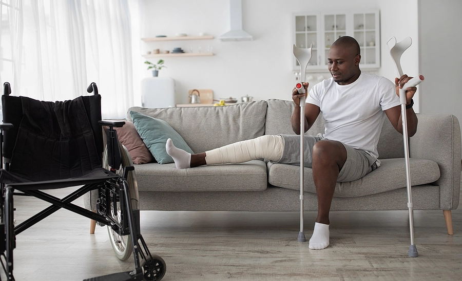 Man sits on his couch with his leg in a cast due to an injury caused by a personal injury accident