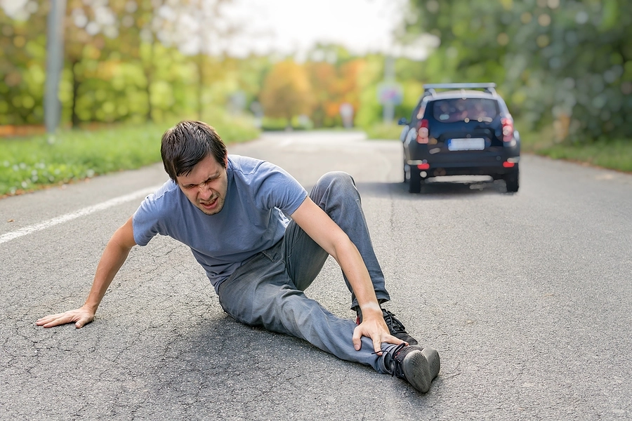 Man clutching his ankle injury in pain caused by a pedestrian accident