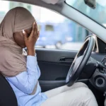 Woman dealing with car accident trauma crying behind the wheel of her vehicle