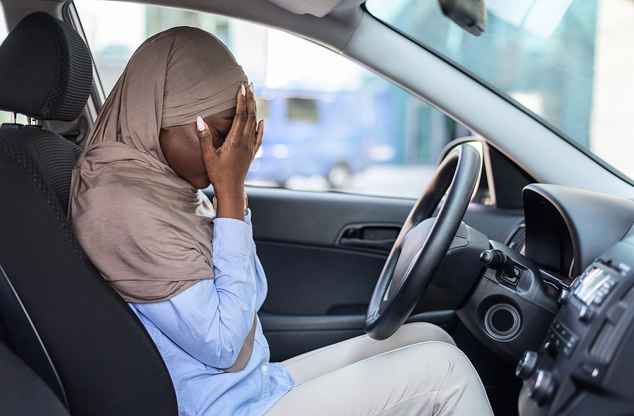 Woman dealing with car accident trauma crying behind the wheel of her vehicle