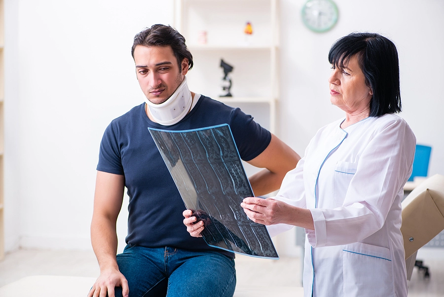 Patient with a neck brace looking at a scan with a doctor after a car accident