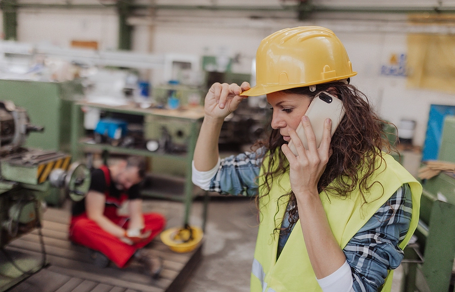 Construction worker in a hard hat calls for medical help for a co-worker who sustained injuries on the job