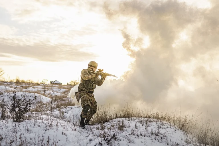 Military service member trying to avoid blast injuries from a nearby explosion in a combat zone during winter