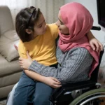 woman in a wheelchair with her young daughter in her lap, experiencing the long-term effects of a spinal cord injury