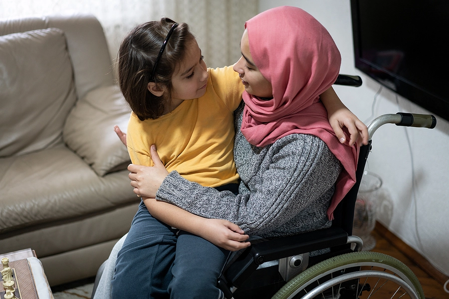 woman in a wheelchair with her young daughter in her lap, experiencing the long-term effects of a spinal cord injury