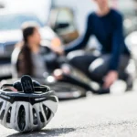 Injured bicyclist is sitting in the street after an accident caused by a driver's negligence