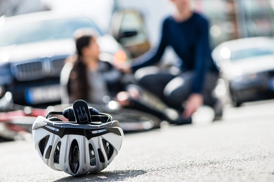 Injured bicyclist is sitting in the street after an accident caused by a driver's negligence