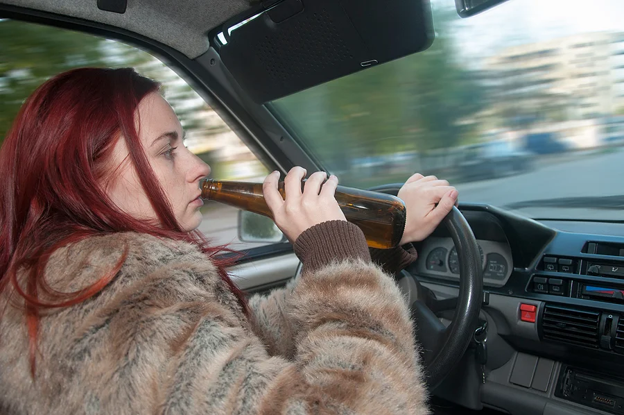 Woman driving fast while drinking a beer