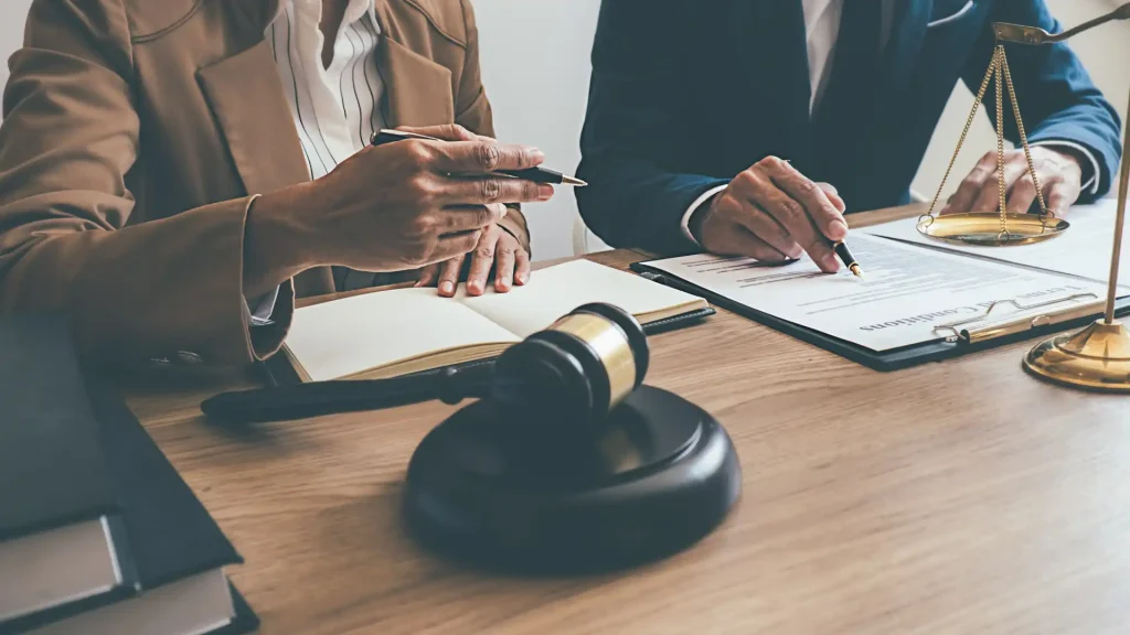 Two professionals discussing legal documents with a gavel on the table.