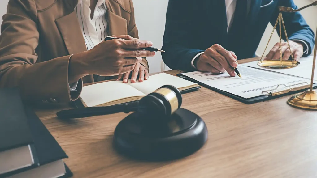 Two people discussing legal documents with a gavel on the table.