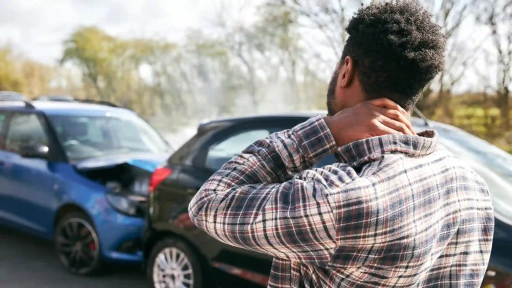 Injured man holding neck after rear-end car accident.