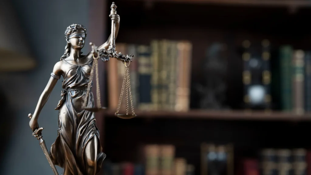 Close-up of Lady Justice statue with bookshelves in the background.