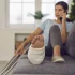 Woman undergoing rehabilitation after a car accident cause her ankle injury sits on the couch talking on the phone