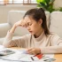 young woman with bills and calculator looking stressed trying to decide when to file for bankruptcy